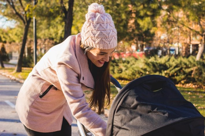 newborn - new mother out in the park with her baby in a pram