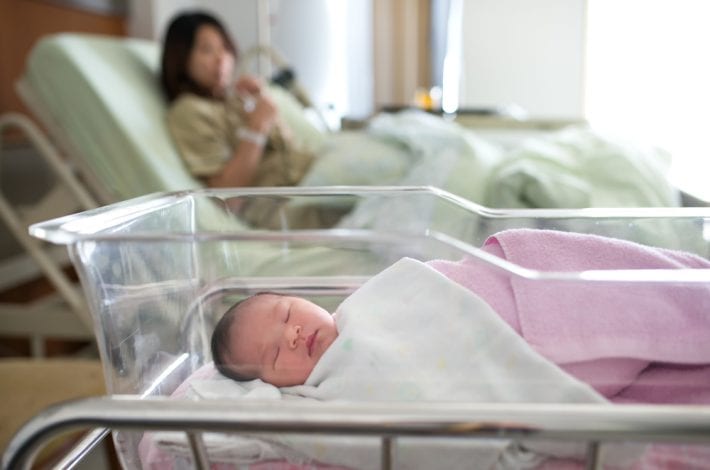 Tips for new mums - new mum in hopsital with newborn asleep in hosptial crib