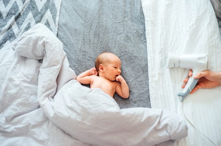 newborn baby lying down with a hairdryer nearby playing white noise