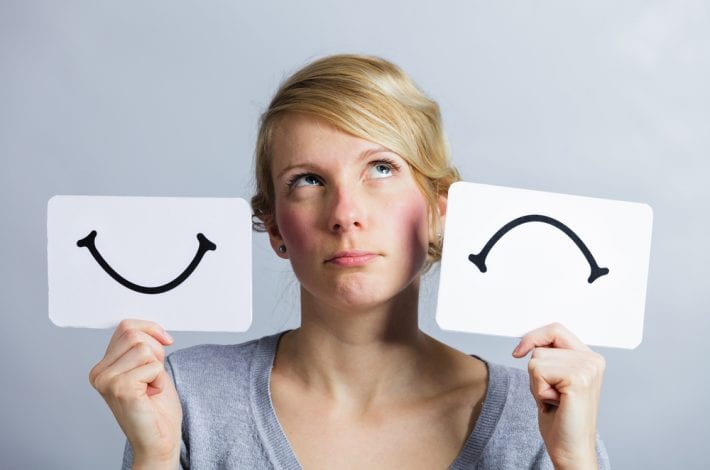 newborn - woman holding up a sign showing a happy and sad face