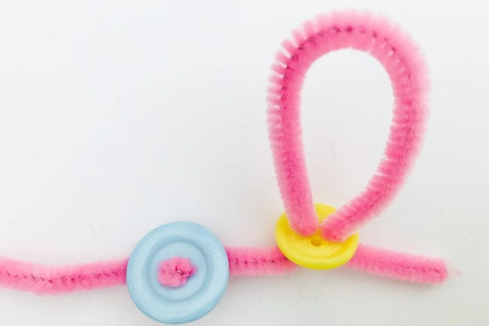 Toddler crafts - Button bracelet threading buttons with pipe cleaner