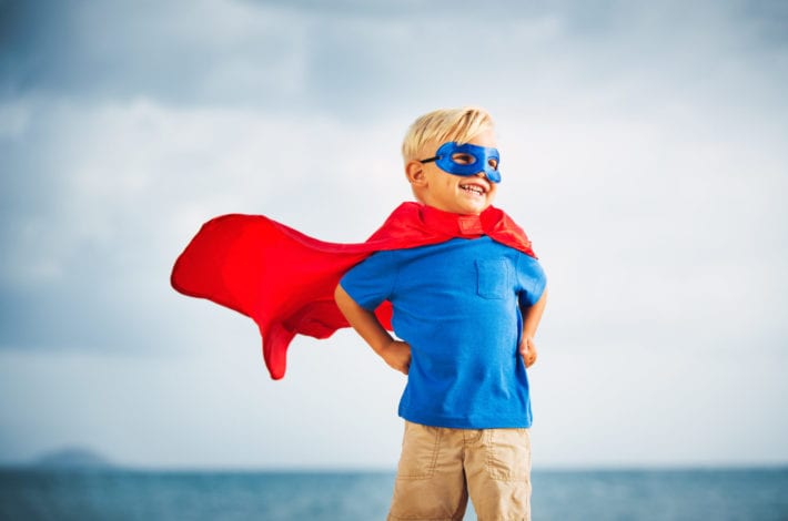 Young boy standing in a superhero pose