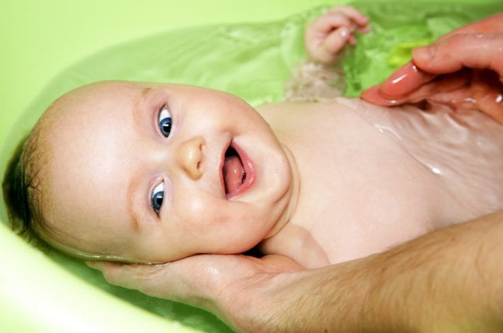 baby having a warm bath and smiling