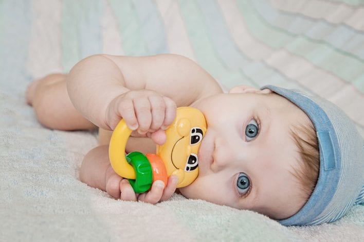 baby holding toy and biting down - baby teething