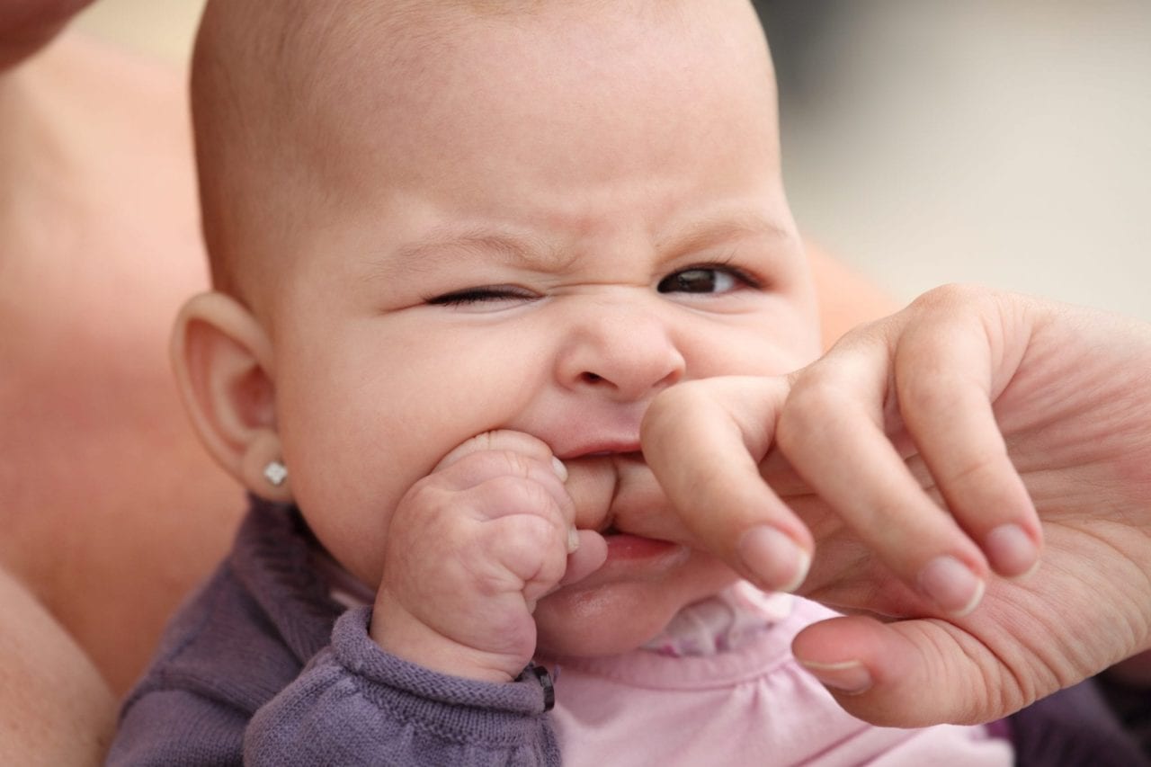 baby teething biting down on a finger