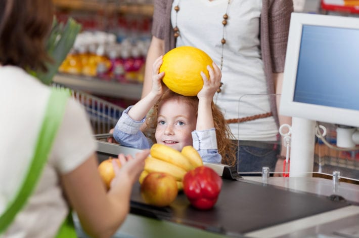 child helping with fruits at the supermarket