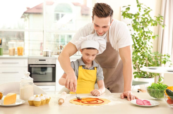 father and son making pizza