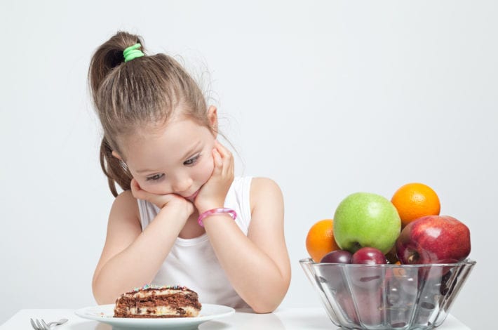 girl looking at cake instead of fruits