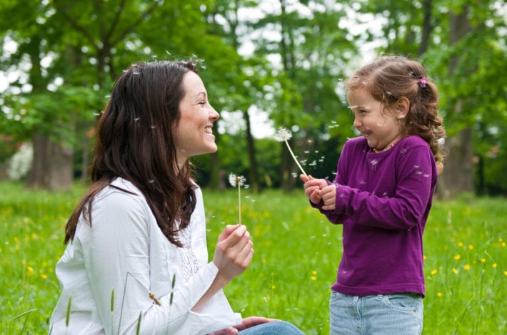 mother and daughter enjoying time together outdoors with dandelion