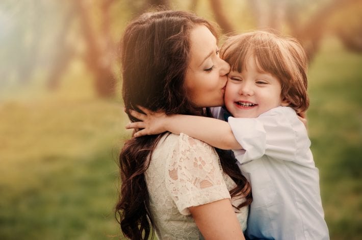 mother praising toddler with hug and kiss