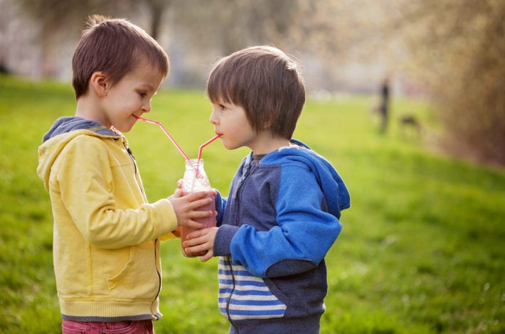 sweet boys sharing a fruit smoothie