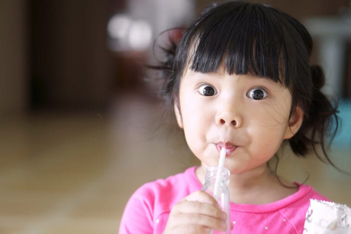 young girl drinking with a straw having a snack