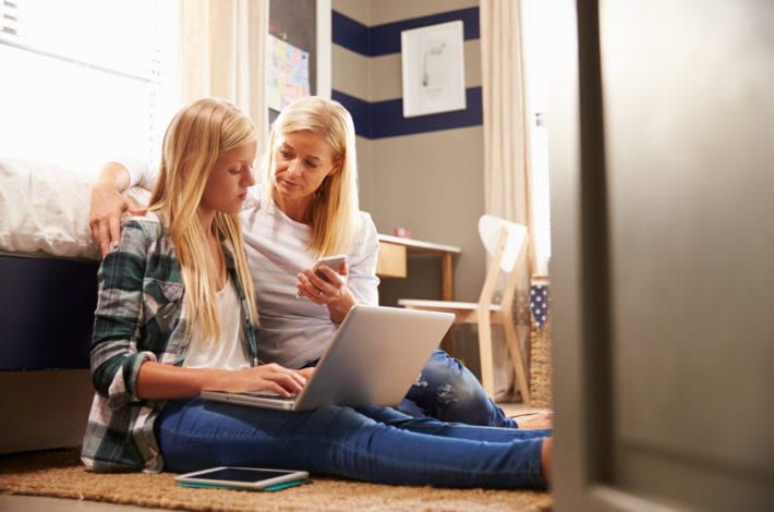 child safe online - mother guiding her teenage daughter on how to use the internet safely